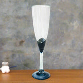 Blown glass champagne flute with black base on wooden table