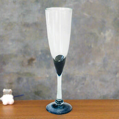Blown glass champagne flute with black base on wooden table